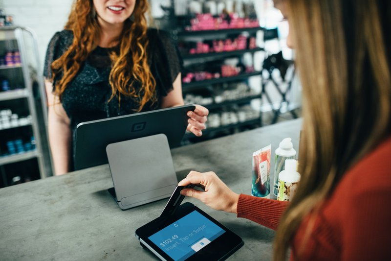 woman holding magnetic card above payment tablet in the store